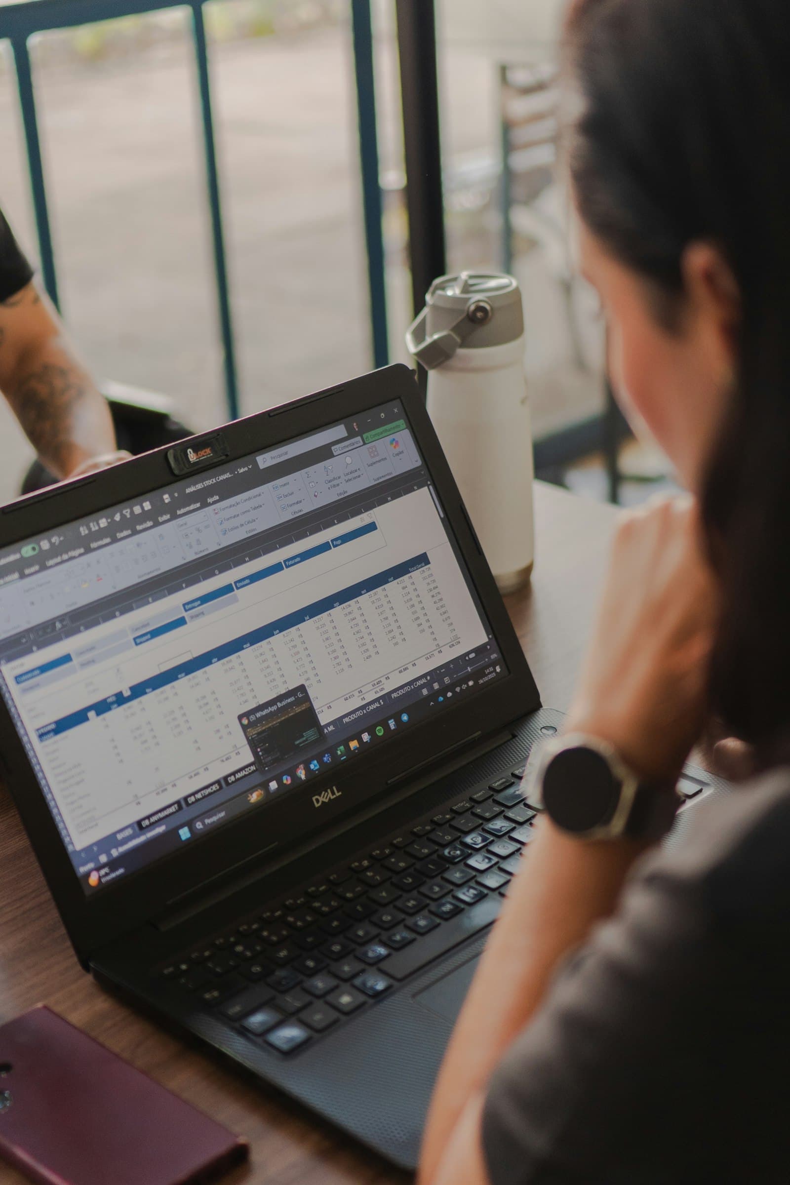 Woman working on a laptop with an expense tracker Google Sheets spreadsheet